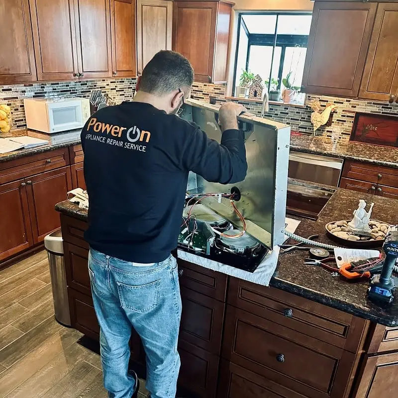 PowerOn Appliance Repair Service technician working on cooktop