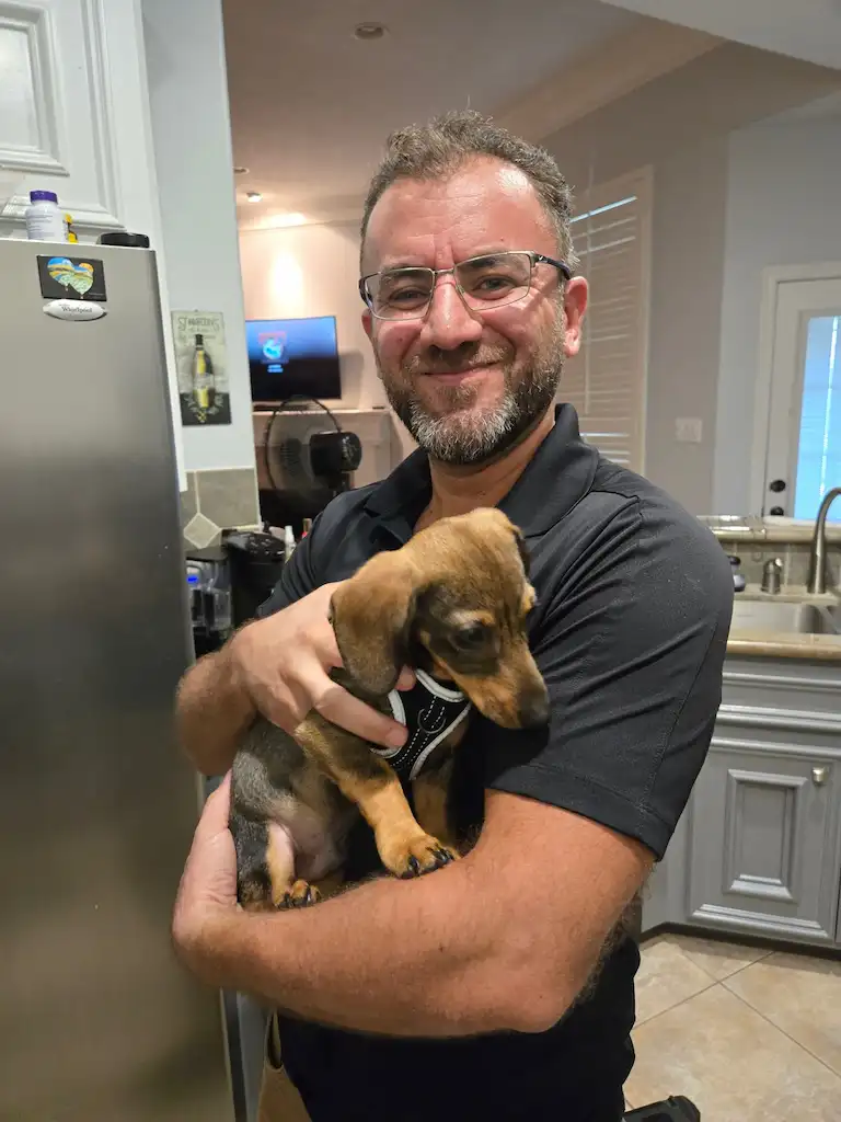 Tiny Dachshund puppy held by a PowerOn technician in Willis