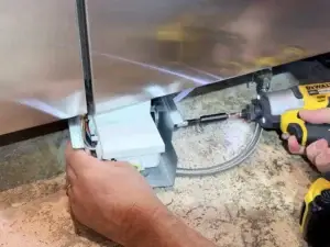 Technician replacing water valve under Thermador built-in refrigerator, The Woodlands TX